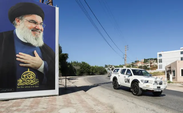 عربة تابعة لقوات حفظ السلام التابعة للأمم المتحدة (اليونيفيل) تمر بالقرب من صورة لزعيم حزب الله حسن نصر الله في قرية العديسة، بالقرب من الحدود اللبنانية الإسرائيلية، جنوب لبنان، 12 يوليو/تموز 2023.