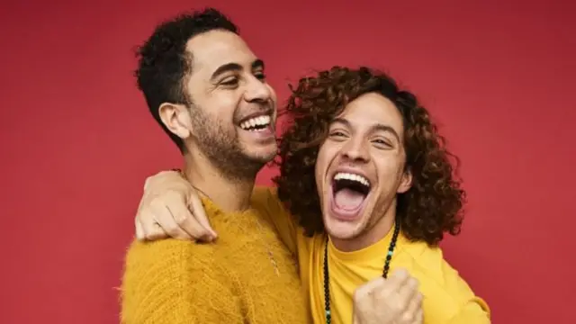 Homens abraçados e sorrindo em foto de estúdio