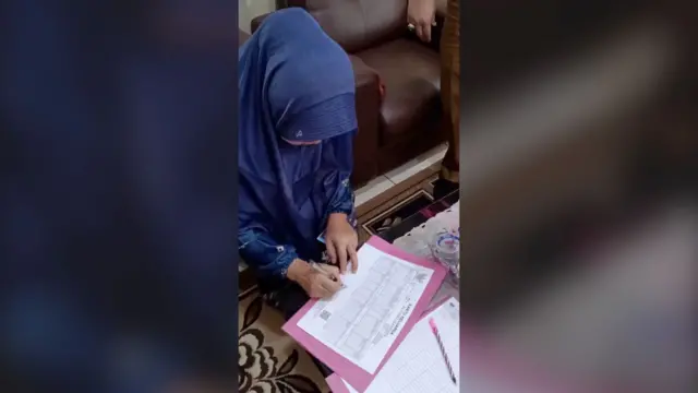 Marliah menandatangani dokumen kartu keluarga (KK) yang baru diterbitkan miliknya. 