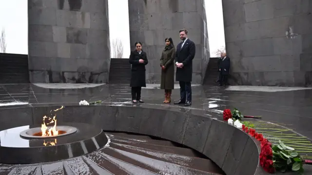 JD Vance ve eşi Erivan'daki soykırım anıtında ayakta durmuş anıtın ortasındaki dairesel yapıda yanan ateşe bakıyor ve kenarda kırmızı ve beyaz güller dizilmiş