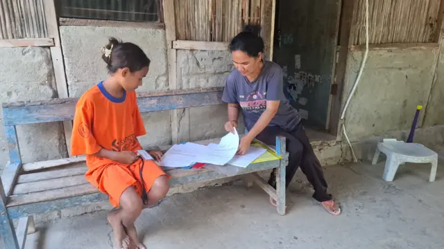 Hani Olivia Guterres (12) dan Maria Novita Tefa (43) sedang mempersiapkan berkas untuk dibawa ke Sekolah Rakyat