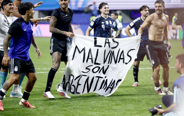 Jugadores de Argentina sostienen una pancarta con el mensaje "Las Islas Malvinas son argentinas" mientras celebran su victoria en el partido de semifinales de la Copa Mundial de la FIFA 2026 entre Inglaterra y Argentina, en Atlanta.