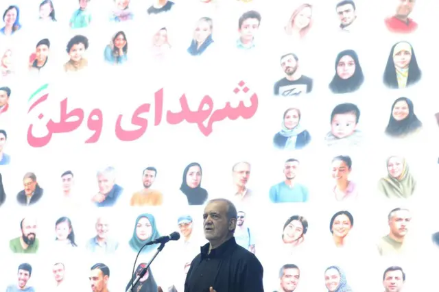 مسعود پزشکیان در وزارت کار در حالی که پشتش تصاویر چهره کشتهشدگان جنگ اسرائیل و ایران دیده می شود و بعضی از زنان در آن بدون حجاب هستند. عکاس: سعید زارعیان