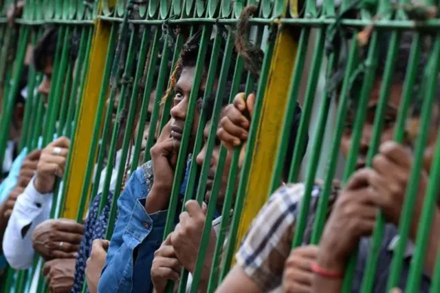 ఊచల నుంచి చూస్తున్న యువకులు