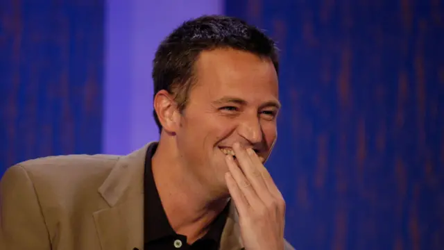 metju peri prekriva lice rukom dok se smeje u televizijskoj emisiji