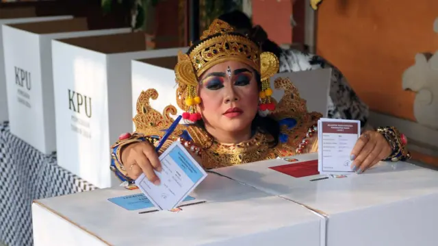 Anggota Kelompok Penyelenggara Pemungutan Suara (KPPS) berbusana tokoh Pandawa memasukkan surat suara ke dalam kotak suara saat Pilkada serentak 2024 di TPS 11 Banjar Blungbang, Desa Penarungan, Badung, Bali, Rabu (27/11/2024).
