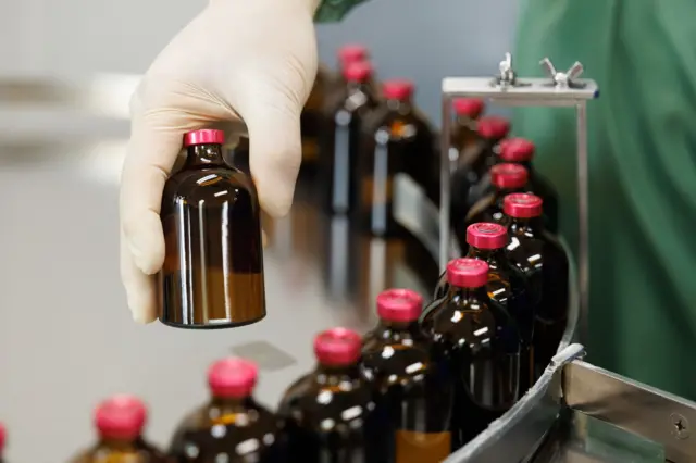 औषधि उत्पादन प्लान्टमा रातो बिर्को भएका बोतलहरू 