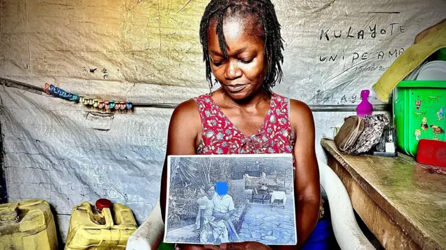 زنی روی یک صندلی سفید نشسته و یک عکس سیاه و سفید از دو نفر را در دست دارد.