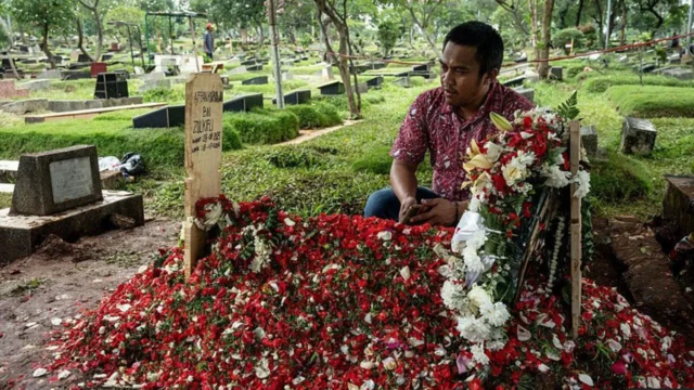 一位朋友在 21 歲的庫爾尼亞萬的墳墓前祈禱。