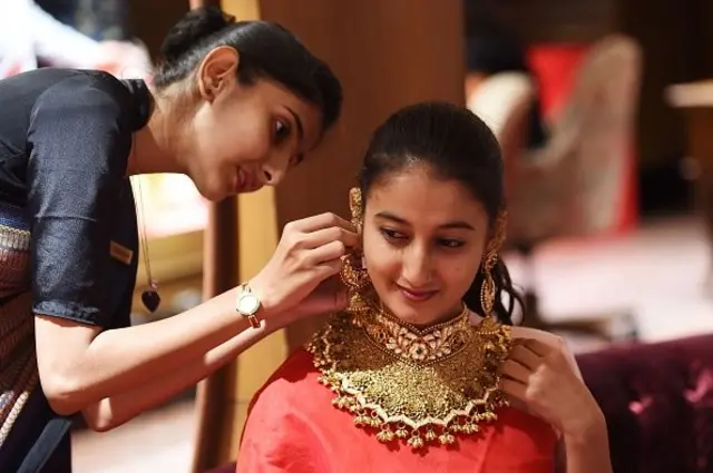 ग्राहकलाई सुनको आभूषण लगाइदिँदै