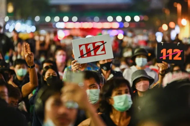 แนวร่วม “ราษฎร” ชุมนุมเมื่อปี 2564 เรียกร้องให้มียกเลิกหรือแก้ไขประมวลกฎหมายอาญา มาตรา 112 หลังผู้ชุมนุมถูกแจ้งความดำเนินคดีด้วยข้อหานี้นับร้อยคน
