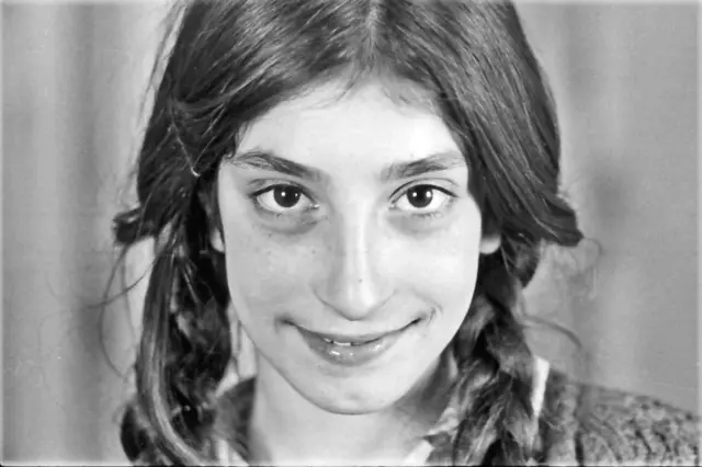 Pülümürlü bir kız çocuğu gülümseyerek poz veriyor. 