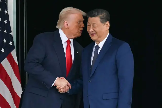 Trump le da la mano al presidente chino, mientras este sonríe.