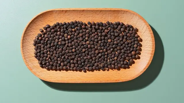 Ahşap bir tabağın içindeki karabiber taneleri.