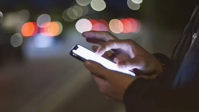 Mãoblaze foguetealguém usando celular na rua à noite