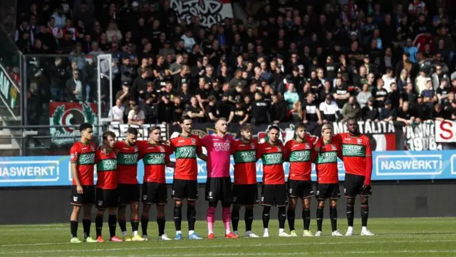 Sebelum laga antara NEC Nijmegen dan Feyenoord FC digelar, para pemain, ofisial, dan para penonton di Stadion De Goffert terlihat menundukkan kepala sebagai tanda penghormatan terhadap para korban di Stadion Kanjuruhan Malang.