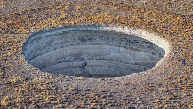 KONYA, TURKIYE - SEPTEMBER 10: An aerial view of professional climbers descending into the approximately 40-meter-deep Inoba Sinkhole, seeking to draw attention to the use of groundwater and the sinkhole hazard caused by drought in the Karapinar district of Konya, Turkiye on September 10, 2025. (Photo by Serhat Cetinkaya/Anadolu via Getty Images)