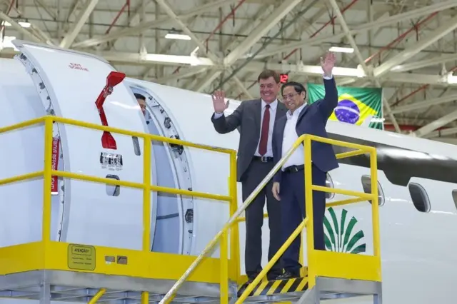 Thủ tướng Phạm Minh Chính và lãnh đạo Embraer vẫy tay chào sau khi rời buồng lái chiếc máy bay của hãng khi ông Chính thăm Brazil vào tháng 9/2023