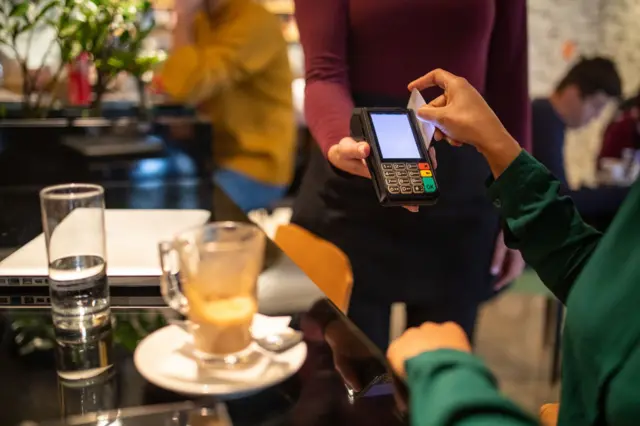 Uma mulher paga a contabonus solverde ptum café com cartãobonus solverde ptcrédito 