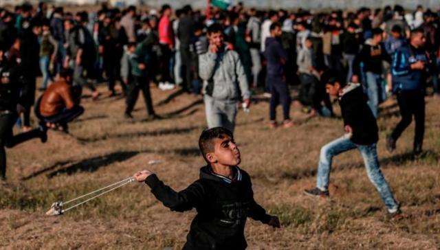 Menino atirando pedra durante manifestação