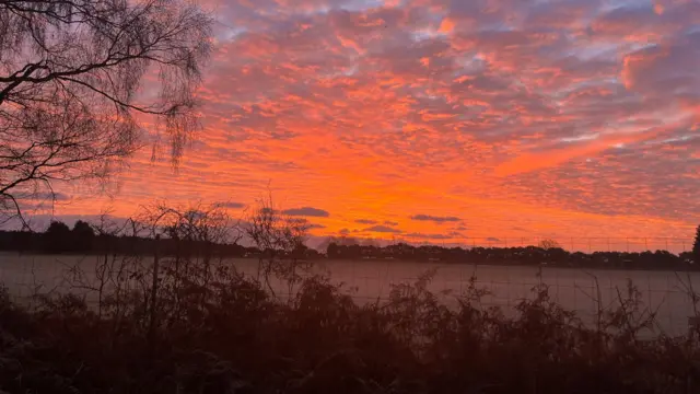 Vista de un campo al amanecer. El cielo se tiñe de rojo y naranja al amanecer.