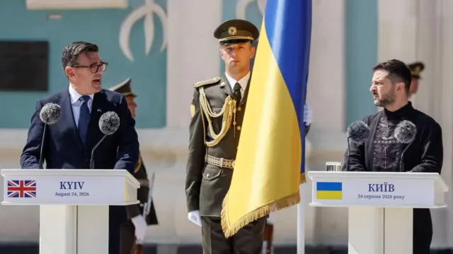 Енди Барнам (лево) и Владимир Зеленски (десно), а између њих је украјинска застава