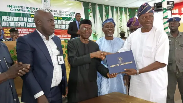 Igbakeji gomina ti wọn ṣẹṣẹ yan l'Ọṣun, Ọmọọba Adewusi n tẹwọ gba iwe ẹri aṣeyege idibo lọwọ alaga ajọ INEC lẹkun iwọ ooru gusu Naijiria, Ọjọgbọn Kunle Ajayi