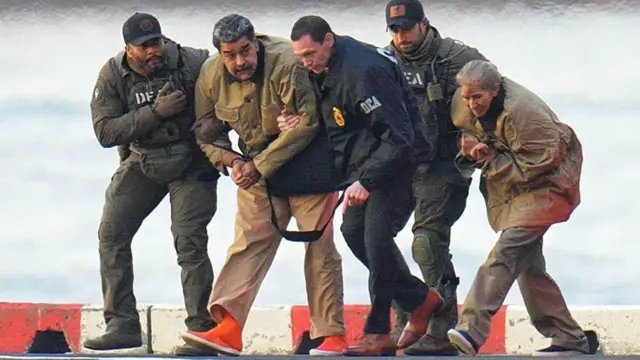 Maduro elleri kelepçeli halde üniformalı güvenlik görevlileri tarafından New York'ta helikoptere bindirilip mahkemeye götürülürken