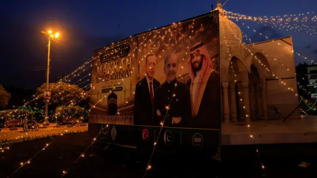 Un cartel decorado con motivos del Pacto de La Meca muestra a los líderes de Turquía, Pakistán y Arabia Saudita.