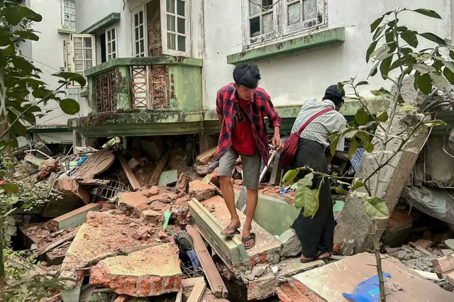 Dos personas, entre los cascotes acumulados junto a un edificio de Naipyidó tras el terremoto.