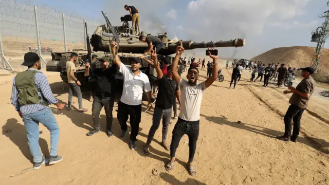 Mayaƙan Al-Qassam Brigade na ƙungiyar Hamas lokacin da suka ƙwace tankar yaƙi ta Isra'ila a kan iyakar Isra'ilar da Zirin Gaza