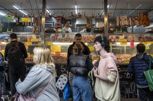 Personas frente a un puesto de carnes y quesos en Uruguay.