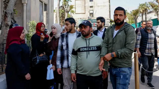 Kurbanların aileleri, devrik lider Beşar Esad döneminde Deraa'da Siyasi Güvenlikten Sorumlu Atef Najib'in davasının ilk gününde, Şam'daki Adalet Sarayı önünde toplandı (26 Nisan 2026).