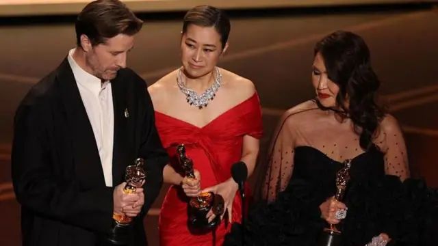 బెస్ట్ యానిమేషన్ ఫీచర్ ఫిల్మ్ విభాగంలో ఆస్కార్ పొందిన కేపాప్ డేమాన్ హంటర్స్ సినిమా దర్శకుడు క్రిస్ అపెల్‌హాన్స్, దక్షిణకొరియా-కెనడా స్క్రీన్ రైటర్ మ్యాగీ కాంగ్, నిర్మాత మిషెల్ వెంగ్