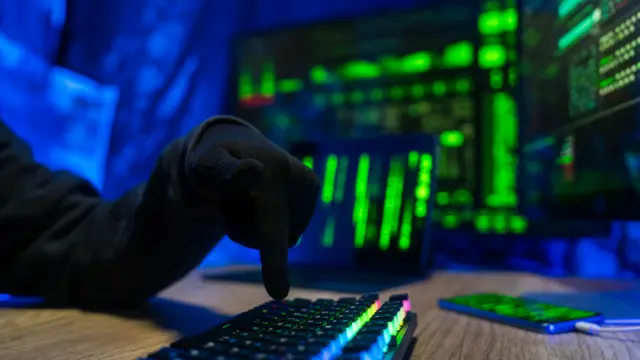 Рука в черной перчатке собирается нажать на клавишу клавиатуры