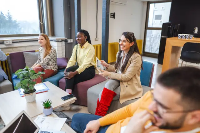 Trabajadores conversan y se ríen en una reunión informal 