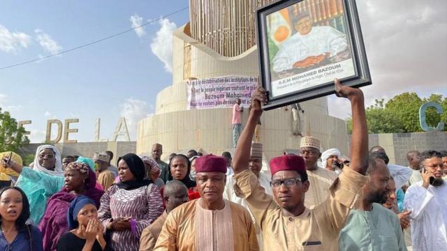 Várias pessoas na rua, onde um homem ergue fotothe best casino online ukMohamed Bazoum