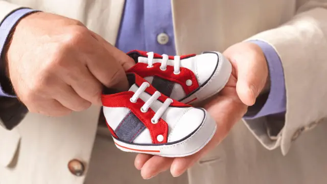 Manos de hombre con zapatitos de niño