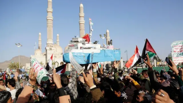 Un Yéménite porte une maquette du Galaxy Leader, navire détourné par les Houthis.