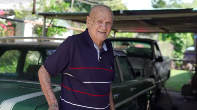 José Rodas delante de su Dodge Dart de color verde.