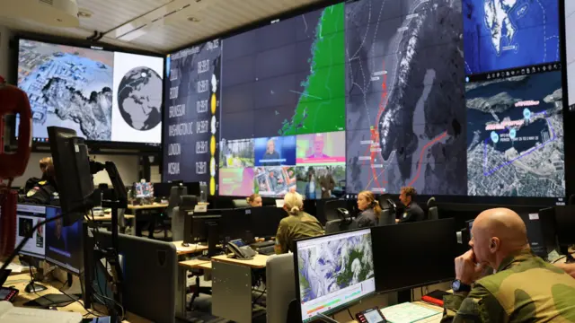 Varios militares en una sala con pantallas gigantes que muestran el mapa de Noruega.