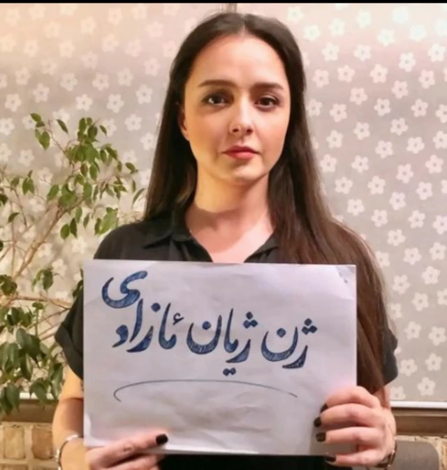 ترانه علیدوستی با کاغذی در دست که روی آن نوشته: ژن، ژیان،ئازادی