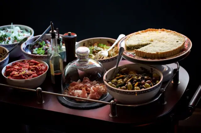 Le chariot d'antipasti comprenant des olives marinées, une salade de thon confit et de haricots blancs, une scafata d'artichauts, des figues, une salade de fromage de chèvre et de roquette