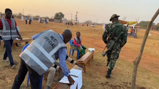 One soja wey hold gun and electoral official for polling station for Malawi