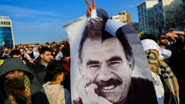 Supporters of the PKK gather in south-eastern Turkey after the group said it would disband. One of them is holding a large poster of the group's jailed leader Abdullah Ocalan
