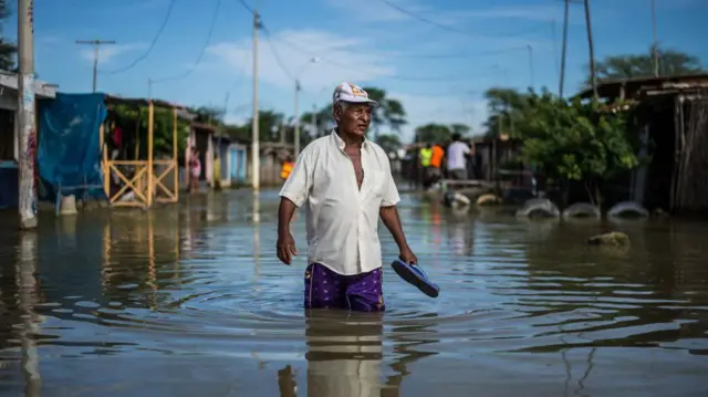 Un hombre camina con el agua por encima de las rodillas en una inundación por el fenómeno de El Niño en Perú