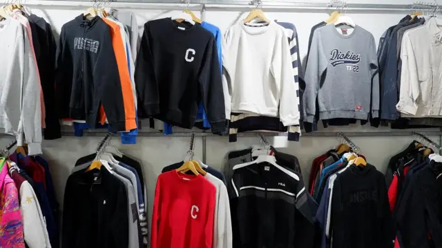 Ratusan helai pakaian bekas berupa kaos, sweater, jaket hoodie, topi, dan sepatu, berderet di lapak baju bekas.