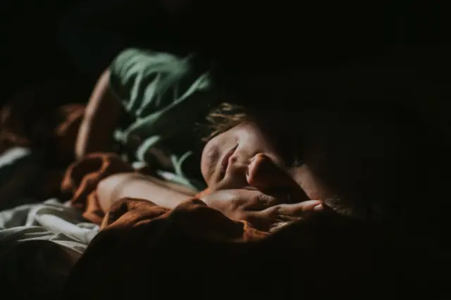 Criança deitada no escuro 