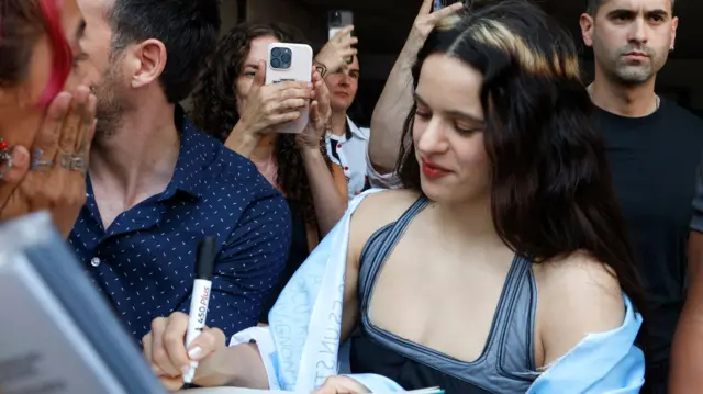 Rosalía, con una bandera Argentina en los hombros, firmando autógrafos en Buenos Aires.