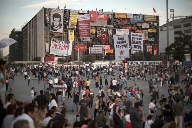 Taksim Meydanı'nda zaman geçiren Gezi Parkı eylemciler. AKM'de çeşitli pankartlar asılı.